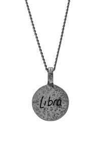 Strieborný okrúhly prívesok s textúrovaným povrchom, vyrytý nápisom "Libra", zavesený na skrútenom retiazke.