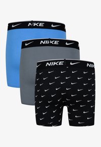 Trīs Nike bokseršortus pāri: viens zils, viens pelēks un viens melns ar baltu svītru rakstu. Katrs no tiem ir ar melnu jostu, kurā ir logs.