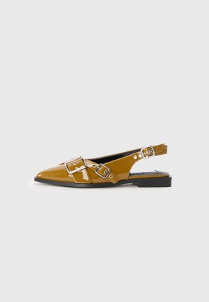 Chaussures à talon slingback à bout pointu en cuir verni jaune moutarde brillant, dotées de deux accents de boucle en argent, d'une semelle plate noire et d'un design de talon ouvert.