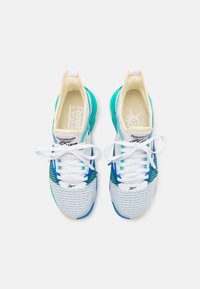 Pantofi sport albi și aqua, cu un superior din plasă, șnururi și o talpă texturată. Logo-ul Reebok vizibil pe limbă și pe panourile laterale.