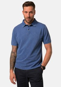 Modrý polo tričko vyrobené z bavlny s klasickým límečkem, manžetou na tři knoflíky a jemným logem. Upnutý střih s krátkými rukávy.