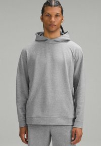 Szary, teksturowany hoodie z przestronnym kapturem, długimi rękawami i luźnym krojem. Tkanina ma subtelny wzór oraz ściągacze przy rękawach.