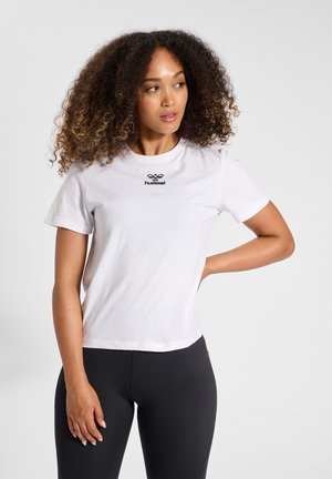Weißes Baumwoll-T-Shirt mit kurzen Ärmeln, Rundhalsausschnitt und einem schwarzen Logo, das in der Mitte der Brust platziert ist. Das Model trägt dazu schwarze Leggings.