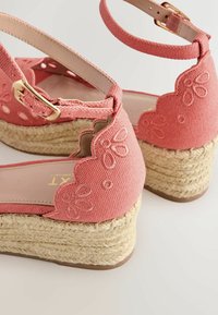 Sandali zeppa in tessuto rosa con cinturini alla caviglia, ricamo floreale, bordi smerlati e suole platform in juta intrecciata.