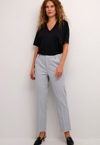Svart V-ringad T-shirt i kombination med ljusgrå, randiga skräddarsydda byxor. Outfiten har en avslappnad passform och en elegant design. Svarta slingback-skor.