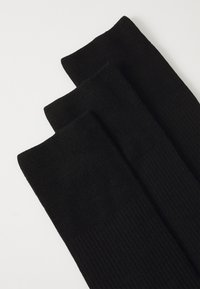 Black ribbed socks in a pack of three, featuring a soft texture and a smooth top cuff design, laid flat with no visible logos.