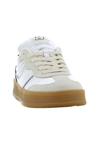 Baskets blanches avec des accents en daim beige, rayures noires, semelle en caoutchouc gomme et matériel argenté sur les lacets ; design à lacets plats.