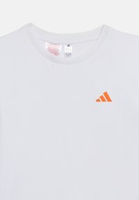 Λευκό αθλητικό πουκάμισο με στρογγυλή λαιμόκοψη από δίχτυ και μικρό πορτοκαλί λογότυπο Adidas στο αριστερό στήθος.