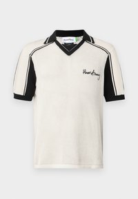 Kurzärmeliges Poloshirt in Creme mit schwarzen Akzenten. Verfügt über einen V-Ausschnitt, texturierten Stoff und ein gesticktes Logo auf der Vorderseite.