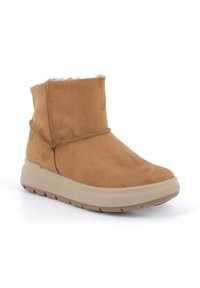 Stivaletti alla caviglia in suede color tan con un morbido interno foderato, una suola piatta in gomma beige e dettagli di cucitura discreti lungo i lati.
