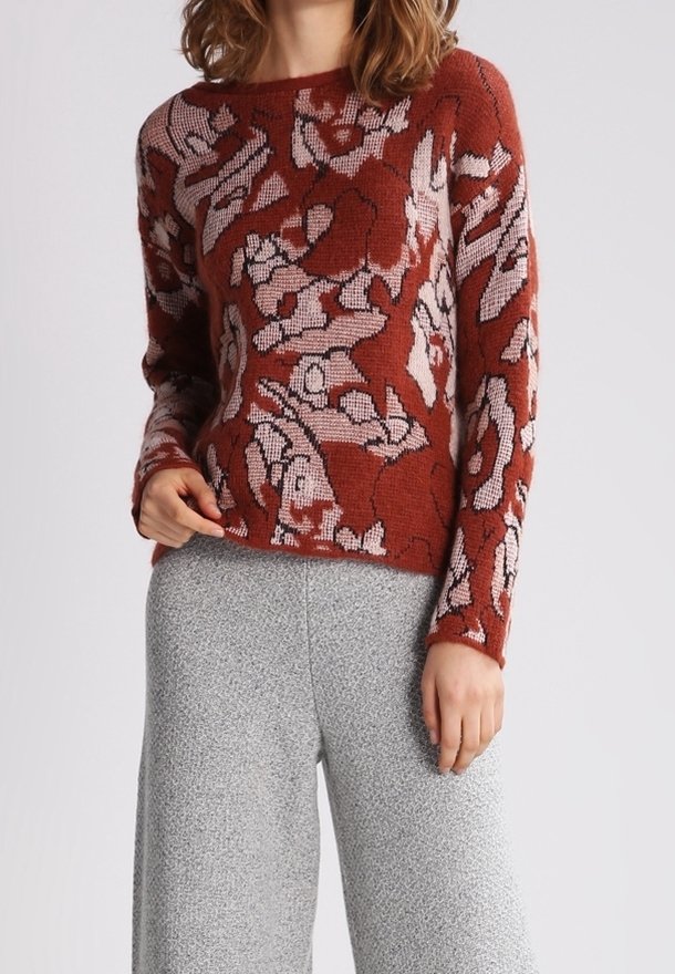 Strikket sweater i rødbrun med blomsterprint i lyse farver. Har en bred halsudskæring og lange ærmer. Kombination med grå vidde bukser.