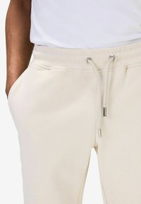 Krämfärgade sweatpants i mjukt tyg, med dragsko i midjan och metalliska detaljer samt sidofickor.