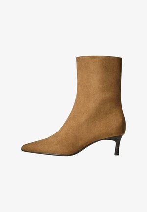 Cizme de gleznă din suede maro, cu vârf ascuțit și toc kitten de înălțime mică. Design elegant și aerisit, cu o textură netedă și accente minime.