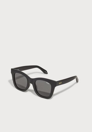 Black rectangular sunglasses with a matte finish, featuring dark lenses and subtle gold branding on the side. Thick, bold frames.
