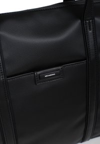 Czarna torba na ramię wykonana z teksturowanego materiału syntetycznego, z gładkim akcentem ze skóry i oznaczeniem marki, oraz wieloma kieszeniami do przechowywania.