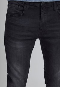 Svarta denimjeans med en mjuk textur, prydda med en klassisk femfickorsdesign och subtila blekningar. Tryckknapp och dragkedja fram.