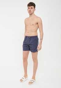 Costumi da bagno navy con cintura elastica e cordoncino, dotati di strisce laterali e materiale leggero e resistente all'acqua.
