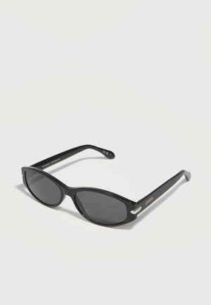 Mustad ovaalsed päikeseprillid tumedate läätsedega ja õhukeste kaartega sangadega, asetatud valgele pinnale.