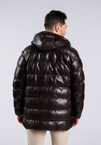 Chaqueta puffer de cuero marrón oscuro con capucha, que presenta secciones acolchadas horizontales y un acabado suave y brillante. Sin hardware o acentos visibles.
