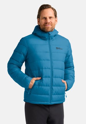 Blaue isolierte Jacke mit Kapuze, ausgestattet mit einem Reißverschluss vorne, vertikalen Steppnähten und Seitentaschen. Markenlogo auf der Brust sichtbar.