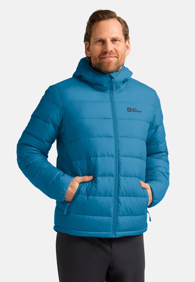 Blaue isolierte Jacke mit Kapuze, ausgestattet mit einem Reißverschluss vorne, vertikalen Steppnähten und Seitentaschen. Markenlogo auf der Brust sichtbar.