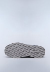 Semelle de sneaker grise avec un motif en vagues, comportant le mot "NAUTICAL" en relief. Le matériau semble être du caoutchouc, conçu pour l'adhérence et la durabilité.