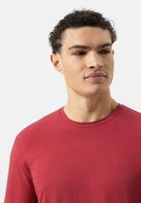 Rotes Langarm-T-Shirt, Rundhalsausschnitt, aus glattem Stoff, enganliegendes Design, minimale Nähte, flacher Saum, keine sichtbaren Muster oder Logos.