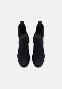 Bottines en daim noir avec une texture lisse, un embout arrondi, des panneaux latéraux élastiques et des languettes pour un enfilage facile.