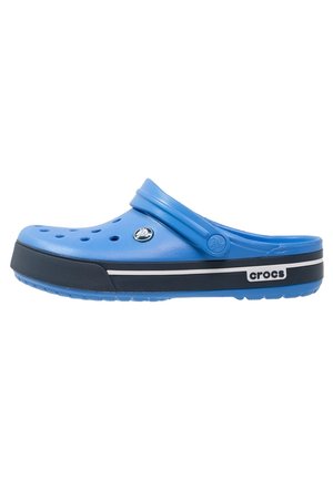 Blauer Crocs Clog mit Lüftungslöchern, einer schwarz-weiß gestreiften Sohle und einem verstellbaren Fersenriemen.