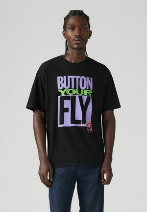 Black cotton t-shirt featuring bold, colorful text: "BUTTON YOUR FLY" in purple and green, with "Levi's 501" in orange. Short sleeves, relaxed fit.
