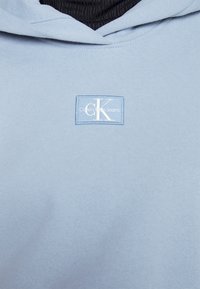 Calvin Klein Jeans BADGE WIDE SLEEVES CROP  HOODIE - Ikdienas džemperis - iceland blue