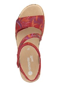 Sandales rouges avec trois brides texturées, dessus à motifs et semelle intérieure beige douce. La semelle est marron clair avec un motif subtil.