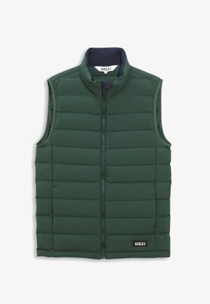 Gilet vert rembourré avec un col haut, fermeture éclair et texture matelassée. Présente une doublure intérieure bleu marine et une étiquette de marque en bas.