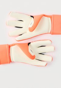 Målvaktshandskar med vit handflata, starkt korallfärgade detaljer och texturerat grepp. Elastisk handledsrem för en säker passform.