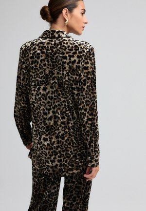 Blouse en imprimé léopard en tissu doux et lisse ; manches longues, col et coupe ample avec un ourlet arrière légèrement plus long.