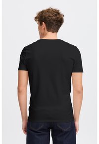 Tricou din bumbac negru cu guler rotund și mâneci scurte, având o textură netedă. Purtați-l cu blugi denim închisi la culoare.