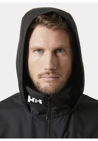 Czarna wodoodporna kurtka z wysokim kołnierzem i kapturem. Posiada zamek błyskawiczny oraz biały logo na kołnierzu. Gładka faktura i dopasowany krój.
