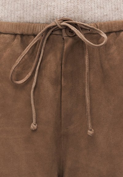 Barna szarvasbőr nadrág húzózsinóros derékrésszel, gombos záródással. Az anyag puha tapintású és sima felületű.