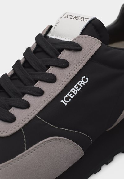 Κοντινό πλάνο μαύρου και γκρι αθλητικού παπουτσιού με μαύρα κορδόνια και λογότυπο "ICEBERG" στο πλάι και στη γλώσσα, που δείχνει λεπτομερή ραφές και υφή.