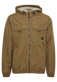 Brown waterproof jacket with a hood, zip closure, two chest pockets, elastic cuffs, and a lightweight design. Features a subtle logo accent.