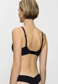Reggiseno nero con spalline regolabili, una texture di tessuto morbido e una chiusura a gancio e occhiello con un discreto dettaglio del logo sull'elastico.