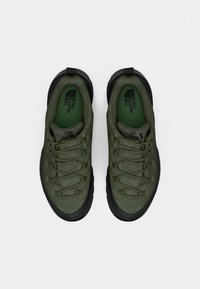 Scarpe da trekking verde oliva con suole in gomma nera. Caratteristiche includono una tomaia testurizzata, stringhe dettagliate e logo sulla soletta.