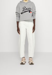 Gray hoodie with "Boss" logo, cream wide-leg pants, and beige sneakers with black and orange accents. Casual athletic outfit.