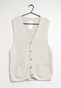 Beżowy dzianinowy kamizelka z dekoltem w serek, zapięciem na sześć guzików i dwiema przednimi kieszeniami. Tkanina ma teksturowany wzór i miękki wygląd.