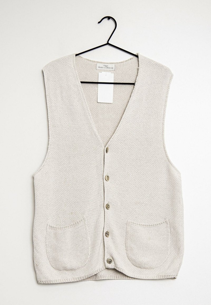 Beżowy dzianinowy kamizelka z dekoltem w serek, zapięciem na sześć guzików i dwiema przednimi kieszeniami. Tkanina ma teksturowany wzór i miękki wygląd.