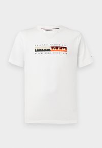 White cotton t-shirt featuring a multicolored graphic that includes text: "COLUMBUS AVENUE NYC HILFIGER ESTABLISHED SINCE 1985."