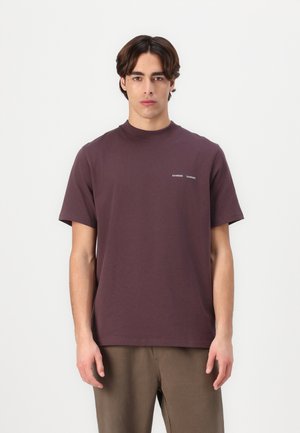 Burgundy puuvillane T-särk lühikeste varrukatega, ümar kaelus ja väike trükitud logo vasakul rinnal. Sile tekstuur, lõdva istuvusega.