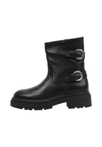 Bottine en cuir noir avec une surface texturée, deux accents de boucle en argent et une semelle épaisse à crantage. Présente une hauteur au niveau du mollet.