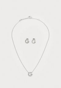 Zilveren juwelenset met een ketting met een ronde hanger en bijpassende studsieraden, beide versierd met heldere kristallen.