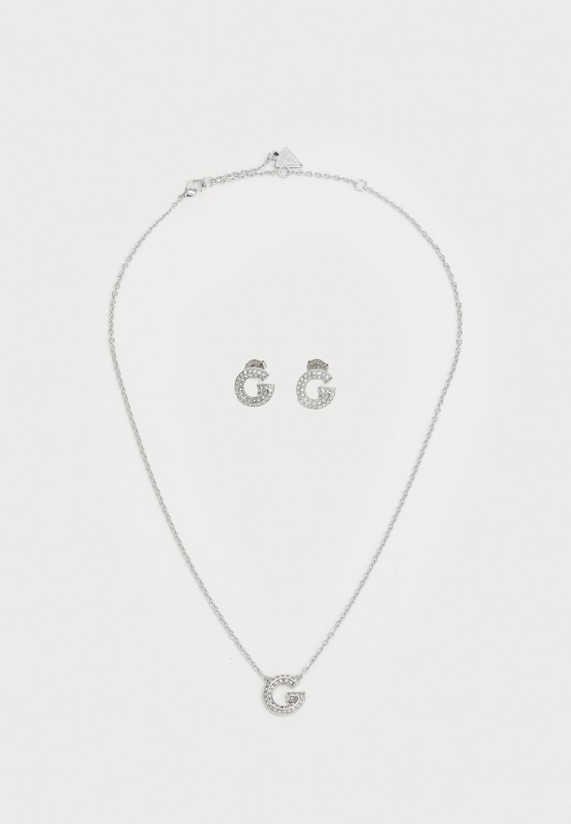 Zilveren juwelenset met een ketting met een ronde hanger en bijpassende studsieraden, beide versierd met heldere kristallen.